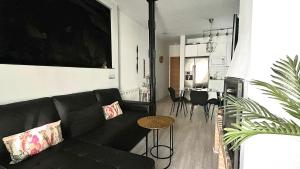 a living room with a black couch and a kitchen at Disfruta Madrid Atocha in Madrid