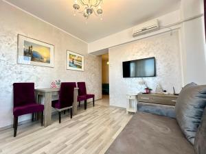 uma sala de estar com uma mesa e uma televisão na parede em BlueSea Summerland Apartments em Mamaia