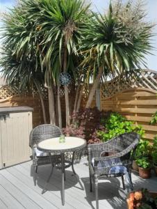 een patio met een tafel en stoelen en palmbomen bij Hot Tub, King Bed, Central, Modern Beach House in Cleethorpes