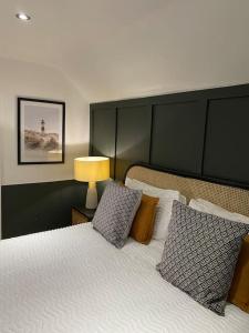 1 dormitorio con 1 cama con almohadas y lámpara en Hot Tub, King Bed, Central, Modern Beach House, en Cleethorpes