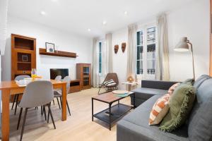 RECENTLY RENOVATED 2 BEDROOM APARTMENT IN EIXAMPLE في برشلونة: غرفة معيشة مع أريكة وغرفة طعام
