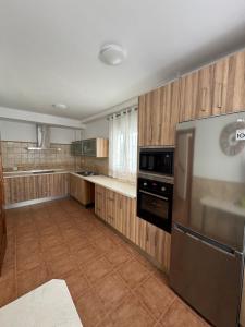 a kitchen with wooden cabinets and a stainless steel refrigerator at Casa a la Vera de la Sierra in Güéjar-Sierra