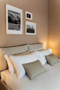a bed with white pillows and pictures on the wall at Cà Bèla - Certosa in Milan