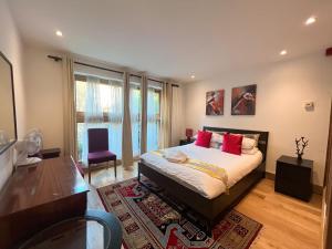 a bedroom with a bed with red pillows and a table at Kensington Apartments in London