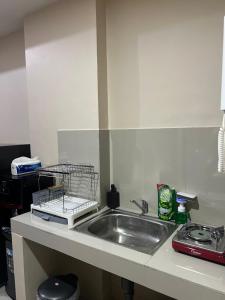 a kitchen counter with a sink and a dish rack at Apartement Vida View, 2BR comfy place by Als in Pampang