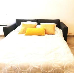 - un lit blanc avec 2 oreillers jaunes dans l'établissement Studio -Centre-ville- Entrée autonome, à Marseille