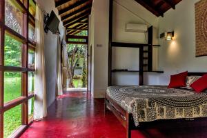 a bedroom with a bed in a room with windows at Sat Nam Village Eco-Hotel in Sigiriya