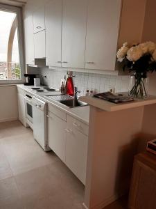 a kitchen with white cabinets and a stove top oven at Appartement Sainte-Cécile in De Panne