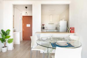 uma sala de jantar com uma mesa de vidro e cadeiras brancas em Apartamento amplio con 4 habitaciones y 2 baños - Great apartment with 4 rooms - 2 baths em Sevilha