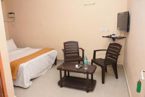 a bedroom with a bed and two chairs and a table at Hotel Park, Thiruvannamalai in Tiruvannāmalai