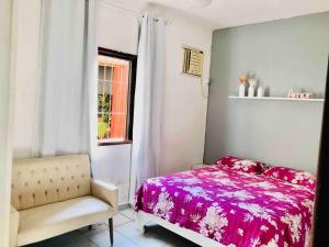een slaapkamer met een bed, een stoel en een raam bij Bertioga Casa pertinho da Praia in Bertioga