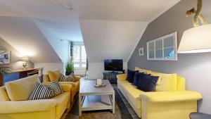 a living room with yellow couches and a tv at Apartmenthaus Binzer Sterne in Binz