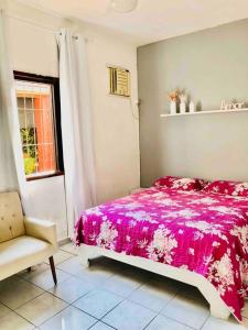 een slaapkamer met een roze bed en een stoel bij Bertioga Casa pertinho da Praia in Bertioga