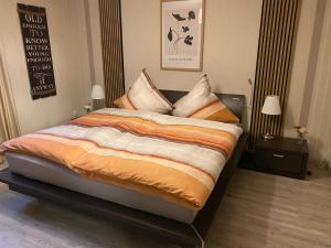 a bedroom with a large bed with orange and white sheets at Ferienwohnung Feiden Eifel-Mosel Lounge in Greimersburg