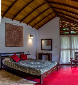 a bedroom with a large bed with red pillows at Sat Nam Village Eco-Hotel in Sigiriya