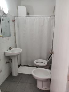 La salle de bains blanche est pourvue de toilettes et d'un lavabo. dans l'établissement Posada de Britopolis, à Colonia Valdense