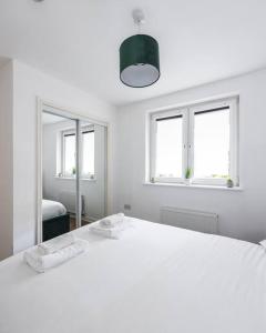 a white bedroom with a white bed and two windows at Stunning 1 BD flat in Lochend Park with a patio in Edinburgh