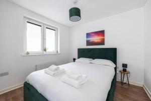 a bedroom with a white bed with two towels on it at Stunning 1 BD flat in Lochend Park with a patio in Edinburgh