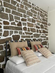 eine Steinmauer hinter einem Bett mit Kissen darauf in der Unterkunft Excellent Rooms Paola's in Olbia