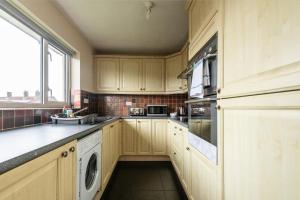 a kitchen with wooden cabinets and a washer and dryer at 3 Bed Apartment - Perfect for Contractors near Liverpool Airport in Hale