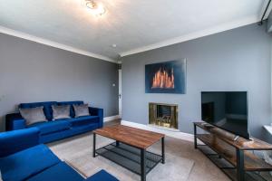 een woonkamer met een blauwe bank en een open haard bij 3 Bed Apartment - Perfect for Contractors near Liverpool Airport in Hale