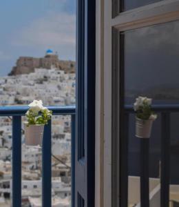 two flower pots on a window with a view of a city at Castelli Studios in Astypalaia Town