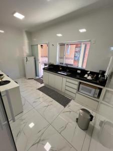 uma grande cozinha com piso em azulejo branco e electrodomésticos em Vila Pepira ViP em Brotas