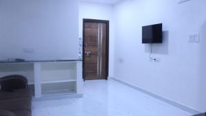 um quarto branco com uma televisão, um sofá e uma parede em Loyal apartment1 BHK Gachibowli em Hyderabad