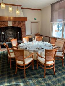 ein Esszimmer mit einem Tisch, Stühlen und einem Kamin in der Unterkunft Hotel & Restaurant Le Cardinal in Poix