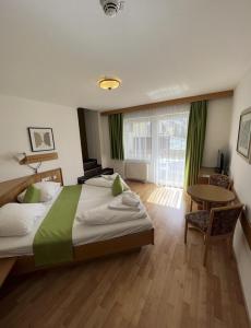 a bedroom with a large bed and a table and a window at Hotel Sonnhof Rauris in Rauris