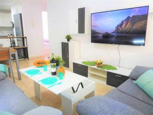 sala de estar con sofá y TV en la pared en Vacaciones Sur Tenerife Ofogar, en San Isidro