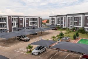un complejo de apartamentos con sombrillas negras en un aparcamiento en Alpha303 en Gaborone