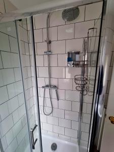 y baño con ducha de azulejos blancos. en Firkinn en Londres