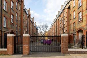 um portão preto em frente a uma fila de edifícios de tijolos em The Shoreditch Collection em Londres