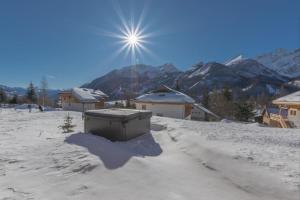 un sol brilla sobre un pueblo cubierto de nieve con edificios en Luxury resort 5* Serrechevalier, en Le Monêtier-les-Bains