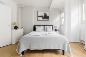 a white bedroom with a large bed with two pillows at The Shoreditch Collection in London