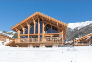 un gran edificio de madera en la nieve en Luxury resort 5* Serrechevalier, en Le Monêtier-les-Bains