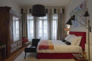 um quarto com uma cama, uma cadeira e janelas em Oporto Loft no Porto
