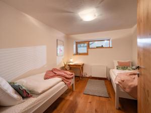 two beds in a room with a desk and a window at Haus Ehammer in Hopfgarten im Brixental