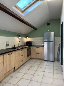 a kitchen with a stainless steel refrigerator and a skylight at Halte à Saint Leu - Maison 5 personnes in Saint-Leu