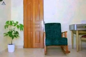 a green chair sitting next to a desk with a plant at Arctic Tern airbnb Mwea 