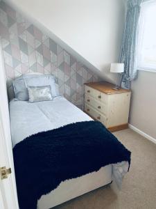 a bedroom with a bed and a dresser and a window at Rosewood Guest House in Swindon