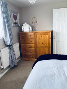 a bedroom with a wooden dresser and a bed at Rosewood Guest House in Swindon