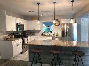 a kitchen with white cabinets and a large island with bar stools at A home away from home in Orlando