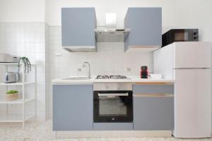 a white kitchen with a stove and a refrigerator at Ampio con ottimi collegamenti per Roma & Aeroporto in Fiumicino