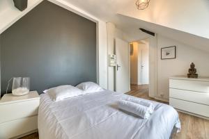 a bedroom with a white bed with a gray wall at Le Cocoon, appartement à proximité du Vieux Marché in Rouen