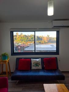 - un canapé bleu dans une chambre avec une grande fenêtre dans l'établissement Departamentos Río Gamboa 2, à Castro
