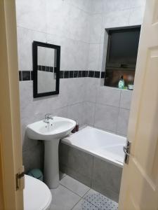a bathroom with a sink and a tub and a toilet at Peaceful Home with Sbo in Pietermaritzburg