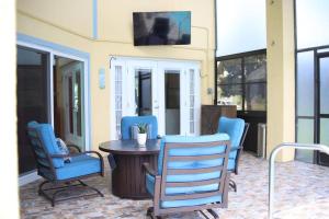 eine Veranda mit blauen Stühlen und einem Tisch und einem Fernseher in der Unterkunft NEW Disney World Villa 4BR, Private Pool Fam Retreat in Davenport