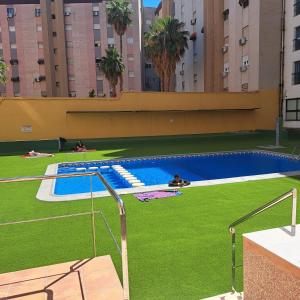 een zwembad met groen gras en gebouwen bij Apartamento Fiesta Sol in Benidorm